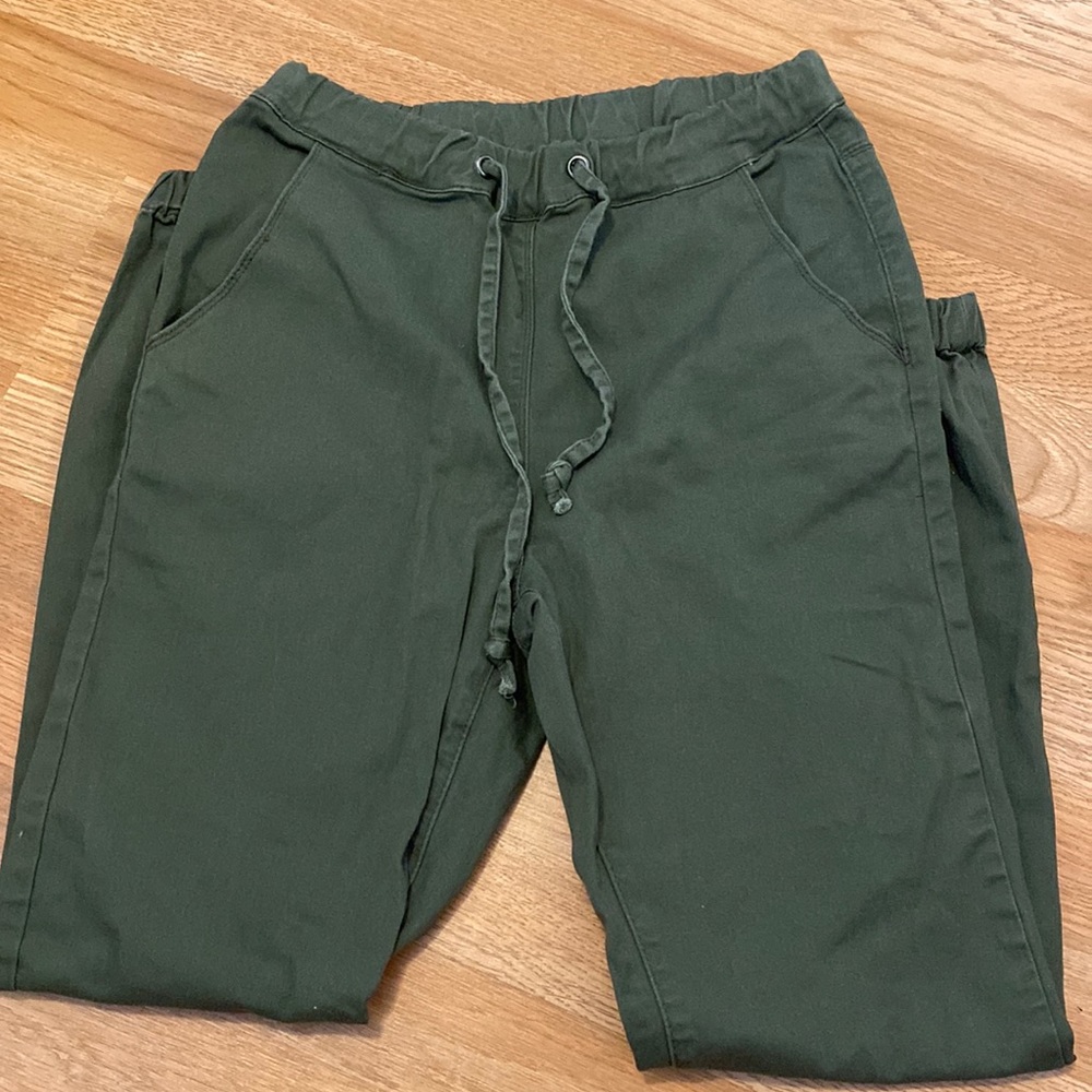 Deep green pants which are tighter at the bottom for a fitted style